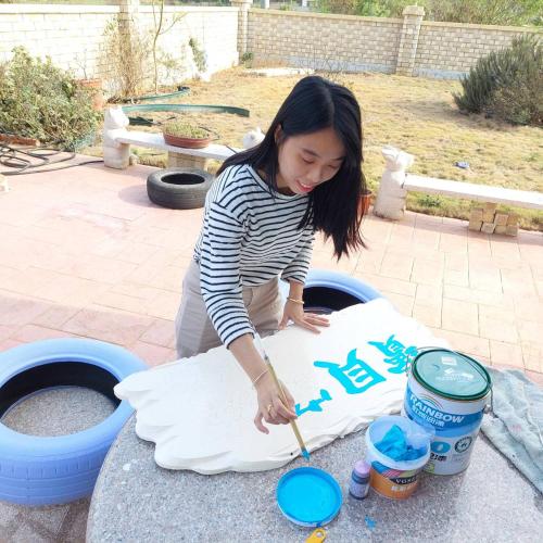 a young woman cutting a piece of paper with a spatula at Baby Family in Jinning