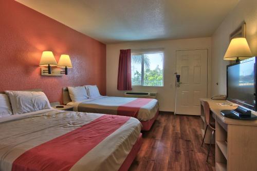 a hotel room with two beds and a flat screen tv at Motel 6-Sacramento, CA - South Sacramento and Elk Grove in Sacramento