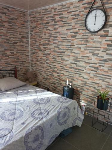 una camera da letto con un muro di mattoni, un letto e un orologio di Chambre privée a Sainte-Suzanne