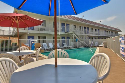 a table and chairs with umbrellas next to a pool at Motel 6-Sacramento, CA - Old Sacramento North in Sacramento