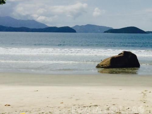 a rock sitting in the water on a beach at Casa Alma Zen - Hostel Boutique & Bistrô Ubatuba in Ubatuba