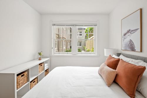 a white bedroom with a bed and a window at Mulwarree Avenue Apartments by Urban Rest in Sydney