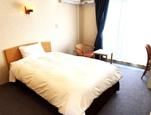 a bedroom with a large white bed and a window at Hotel Kosaka Gold Palace in Kosaka