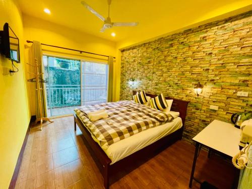 a bedroom with a bed with a brick wall at Shin Sane Guest House in Mae Salong