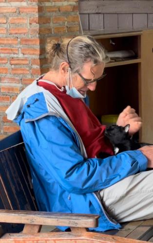 a woman sitting on a bench holding a cat at Shin Sane Guest House in Mae Salong