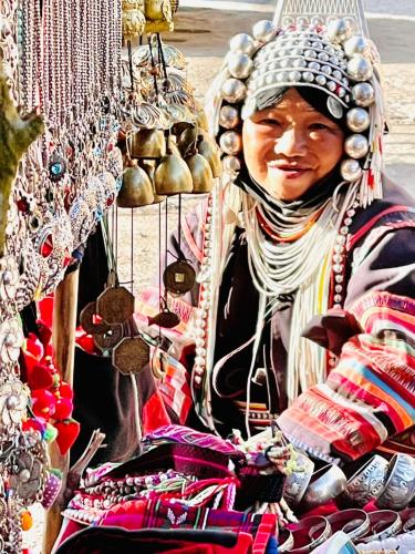 a woman wearing a headdress sitting next to a pile ofellery at Shin Sane Guest House in Mae Salong
