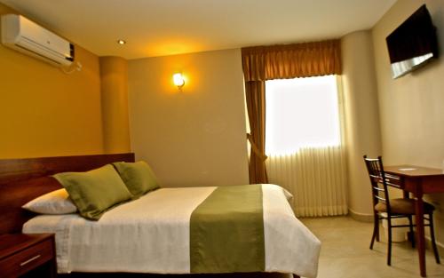 a bedroom with a bed and a table and a window at Hotel Puerto Banana in El Guabo