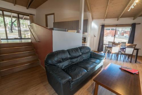 a living room with a leather couch and a table at Wonderland Cottages in Halls Gap
