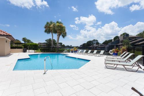 a swimming pool with lounge chairs and palm trees at Deer Run 9767 in Ponte Vedra