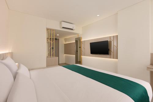 a white bedroom with a large bed and a television at Elsotel Purwokerto By Daphna Management in Purwokerto