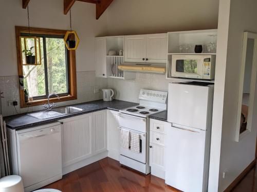 a kitchen with white cabinets and a white refrigerator at Romantic Cabin Escapes Barrington Tops - Lorikeet in Bandon Grove