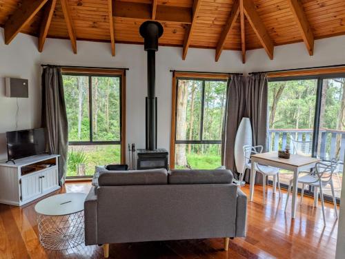 a living room with a couch and a stove at Romantic Cabin Escapes Barrington Tops - Lorikeet in Bandon Grove