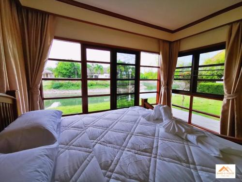 a bedroom with a large bed with a large window at Sand-D House Pool Villa C18 at Rock Garden Beach Resort Rayong in Mae Pim