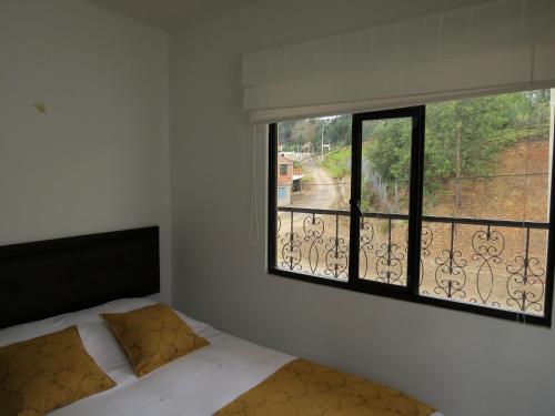a bedroom with a bed and a large window at Hotel el mesón Tinjacá in Tinjacá