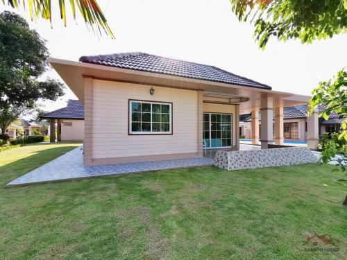 een huis met een gazon ervoor bij Sand-D House Pool Villa A8 at Rock Garden Beach Resort Rayong in Ban Ao Makham Pom