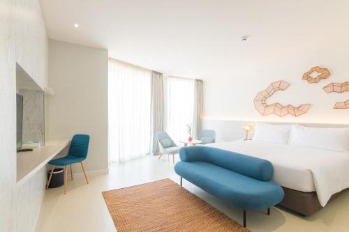 a bedroom with a large bed and blue chairs at VELA Dhi Udon Thani in Udon Thani