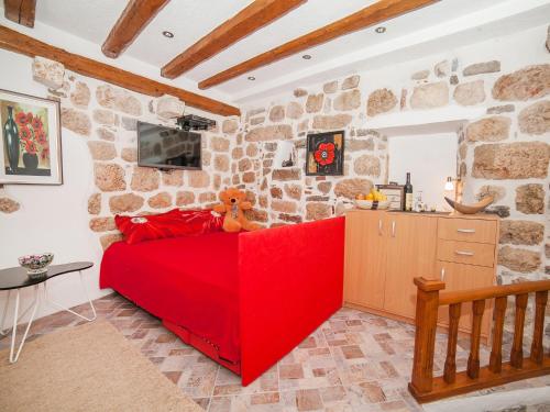- un lit rouge dans une chambre dotée d'un mur en pierre dans l'établissement Apartment Alexandra, à Kotor