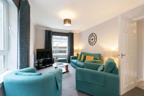 ein Wohnzimmer mit 2 blauen Sofas und einem TV in der Unterkunft Two Bedroom Ground Floor Flat in Bridge of Allan