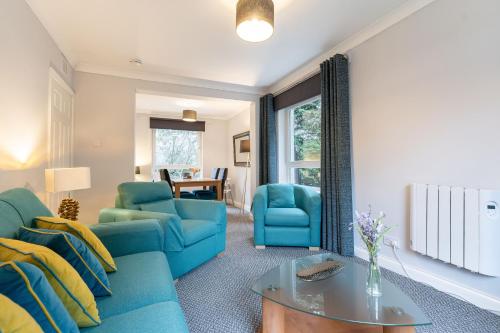 a living room with blue chairs and a table at Two Bedroom Ground Floor Flat in Bridge of Allan