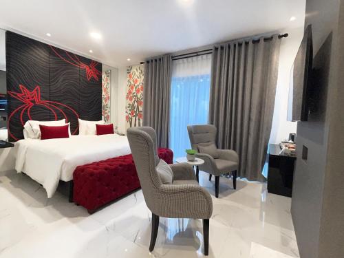a bedroom with a bed and chairs and a television at MORITZ SMART BANDUNG in Bandung