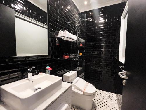 a black tiled bathroom with a sink and a toilet at MORITZ SMART BANDUNG in Bandung