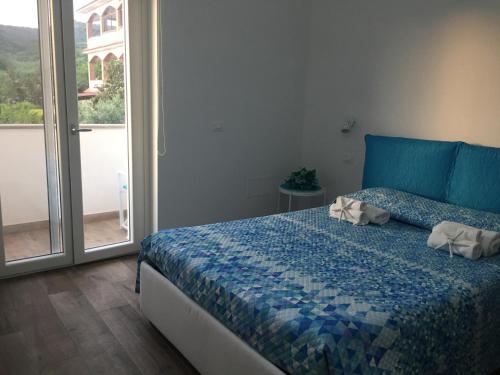 sypialnia z łóżkiem z niebieską kołdrą i oknem w obiekcie Laris w mieście Castellabate