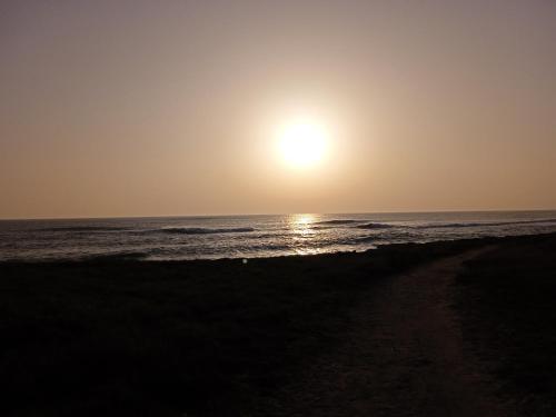 a beach with the sun setting over the ocean at Ti Korelo Fort Bloqué in Ploemeur
