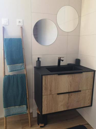 een badkamer met een wastafel en 2 spiegels bij A l'orée du bois in Romanswiller