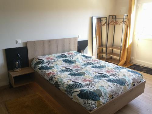 1 Schlafzimmer mit einem Bett mit Blumenbettdecke in der Unterkunft A l'orée du bois in Romanswiller