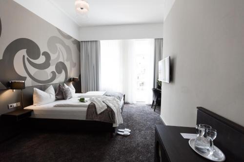 a hotel room with a bed and a desk at Hotel SONATA in Baden-Baden