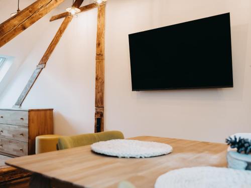 a wooden table with chairs and a television on a wall at Vila Na Landeku in Ostrava