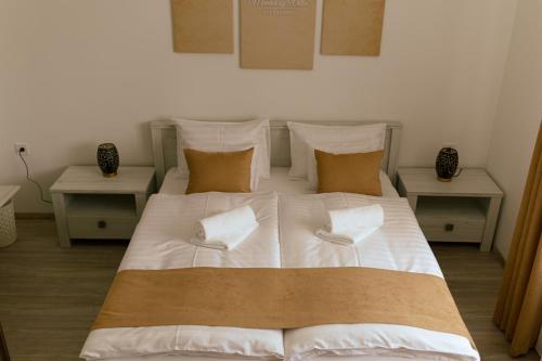 a large bed with white sheets and pillows at Munkácsy Villa - Szekszárd in Szekszárd