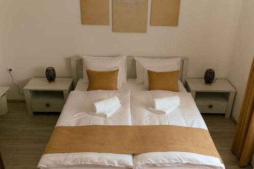 1 cama grande con sábanas y almohadas blancas en Munkácsy Villa - Szekszárd, en Szekszárd