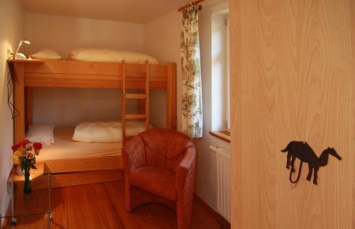 a bedroom with a bunk bed and a chair at Gut Settin am See - Ferienhäuser in Settin