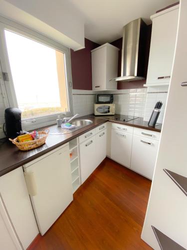 une cuisine avec des armoires blanches, un évier et une fenêtre dans l'établissement The Beach, à Calais