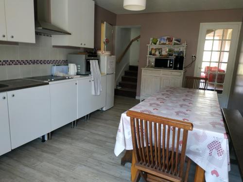 une cuisine avec une table et des placards blancs dans l'établissement La Maison Du Lavoir, à Payroux