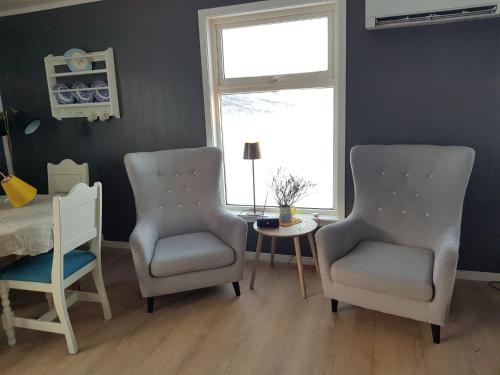 two chairs and a table in a room with a window at T-R Huset i Hellosan in Bøstad
