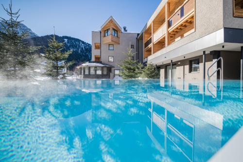 une piscine d'eau bleue devant un bâtiment dans l'établissement Hotel Laurin, à Dobbiaco