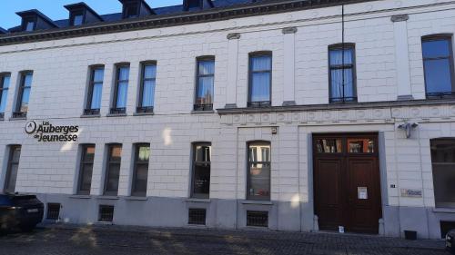 budynek z białej cegły z brązowymi drzwiami w obiekcie Auberge de Jeunesse de Tournai w mieście Tournai