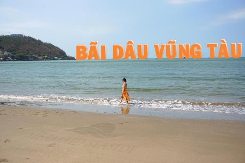 een persoon die op het strand loopt met een bord dat bal davis vleugel leest bij Mermaid Seaside Hotel in Vung Tau
