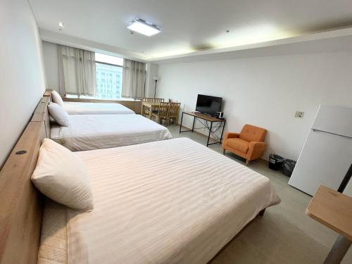 um quarto de hotel com duas camas e uma cadeira em Incheon Airport Guesthouse em Incheon