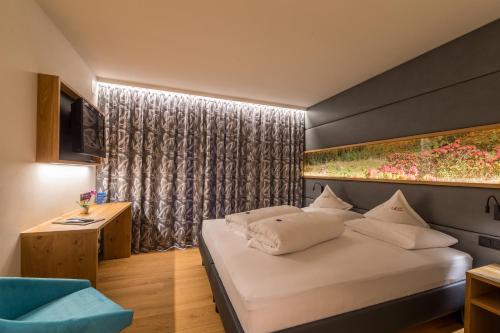 Un dormitorio con una gran cama blanca y una ventana en Garni Marianne, en Malles Venosta