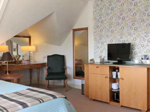 a bedroom with a bed and a tv and a chair at Higher Faugan in Penzance
