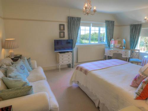 a bedroom with a bed and a couch and a television at Higher Faugan in Penzance
