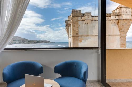 a room with a window with a view of the ocean at La Tonnara di Bonagia Resort in Valderice