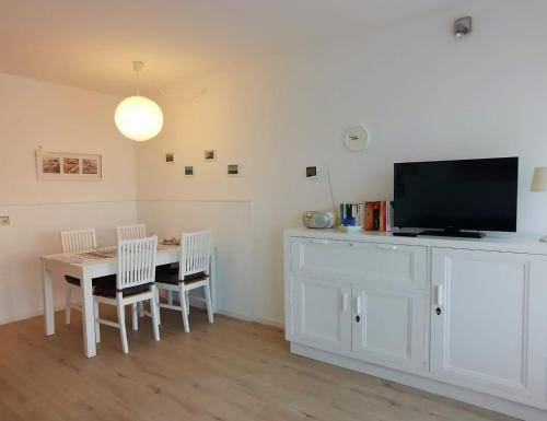 een eetkamer met een tafel met stoelen en een tv bij Haus Berlin 58 in Großenbrode