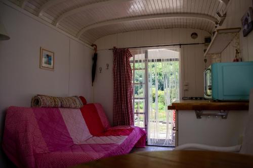 - un salon avec un canapé rose et une porte coulissante en verre dans l'établissement pipowagen Blagour gelegen aan waterbron, à Lachapelle-Auzac