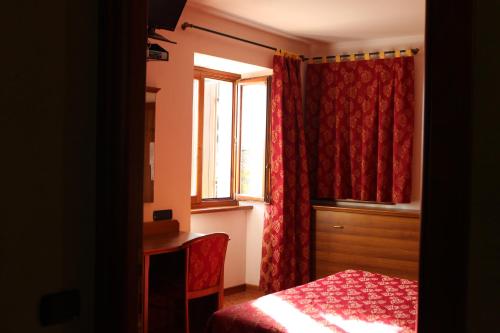 a bedroom with a red bedspread and red curtains at Cà Del Ponte in Costermano