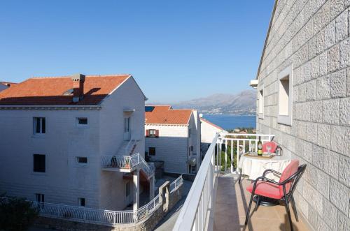 balcón con silla roja y vistas al agua en Apartments Senjo en Cavtat
