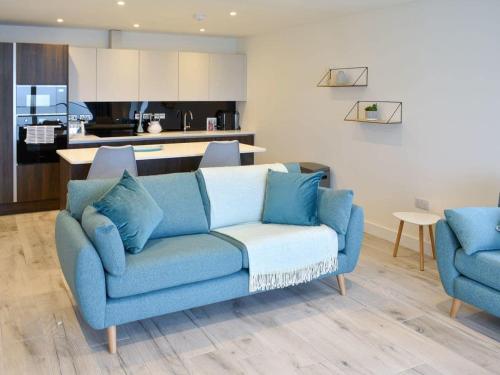 un soggiorno con divano blu e una cucina di Royal Cliff Luxury Apartments - The Bay a Sandown
